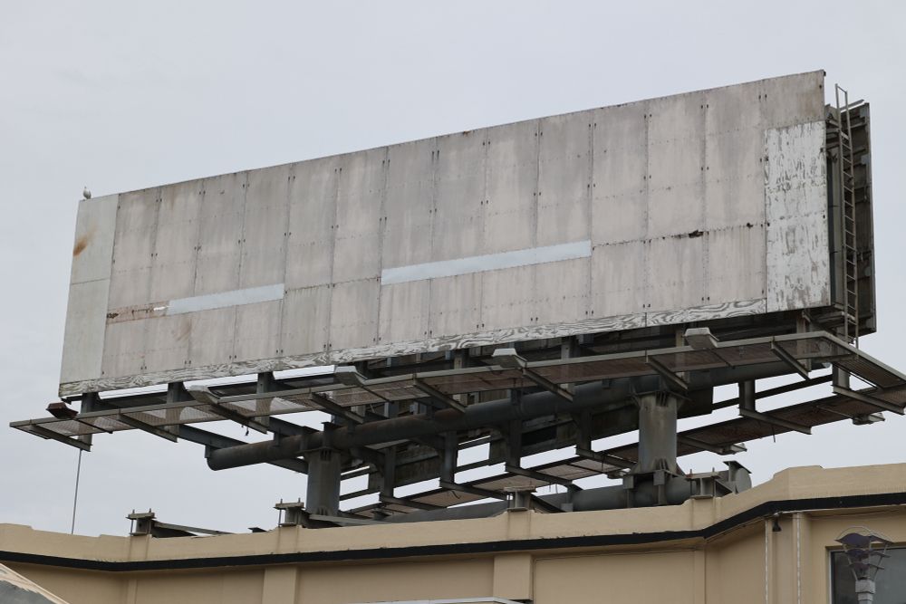 A blank and dilapidated billboard with dingy patches and exposed wood 