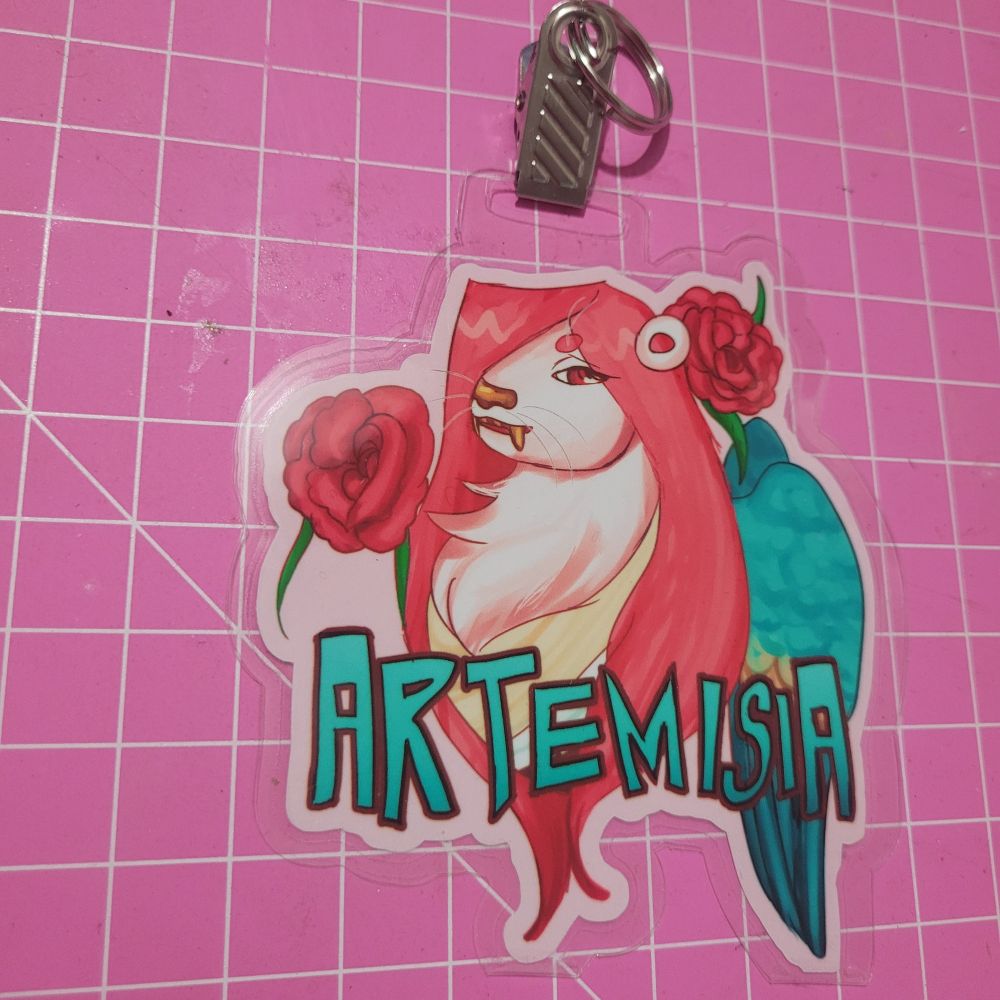 Badge of a baby pink otter with long straight hot pink hair, golden fangs and kingfisher bord wings. Surrounding them are oleander flowers. Below it is written "artemisia" ( their name) in aqua letters with thick dark red outlines.
