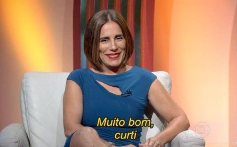 Glória Pires sentada em um sofá, sorrindo, com a legenda "Muito bom, curti".