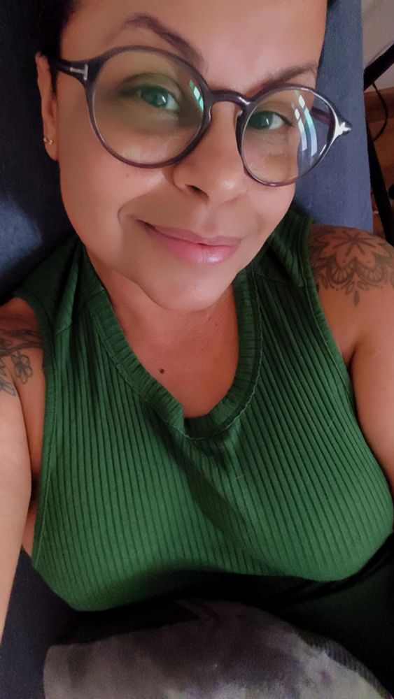 Estou deitada no sofá. Uso óculos e vestido verde.