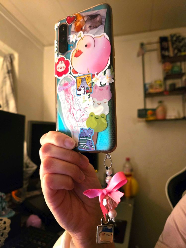 A phone case packed with cute stickers. A custom tamagoshi and pink bow charm.
