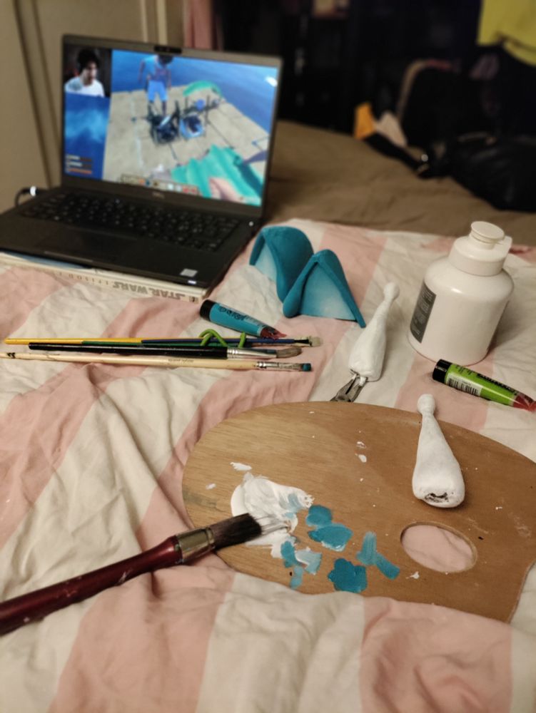 Small painted ears and white antennae laying to dry after being painted. With a video of Markiplier in the background on a laptop.