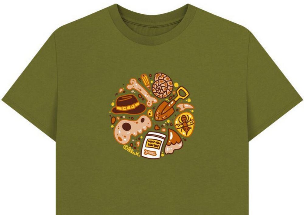 olive green shirt with a circle of archaeology motifs in cream, brown and yellow: a indiana jones hat, a dinosaur skull, a femur, a pencil, an ammonite, a shovel, a baggie with a bone, two teeth, a mosquito in amber.