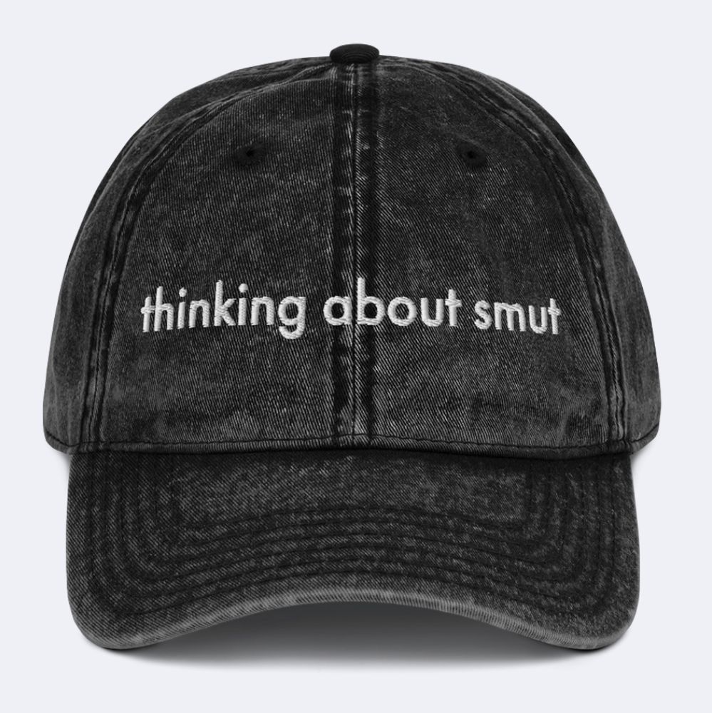 Distressed black denim dad hat with white embroidery reading "thinking about smut"