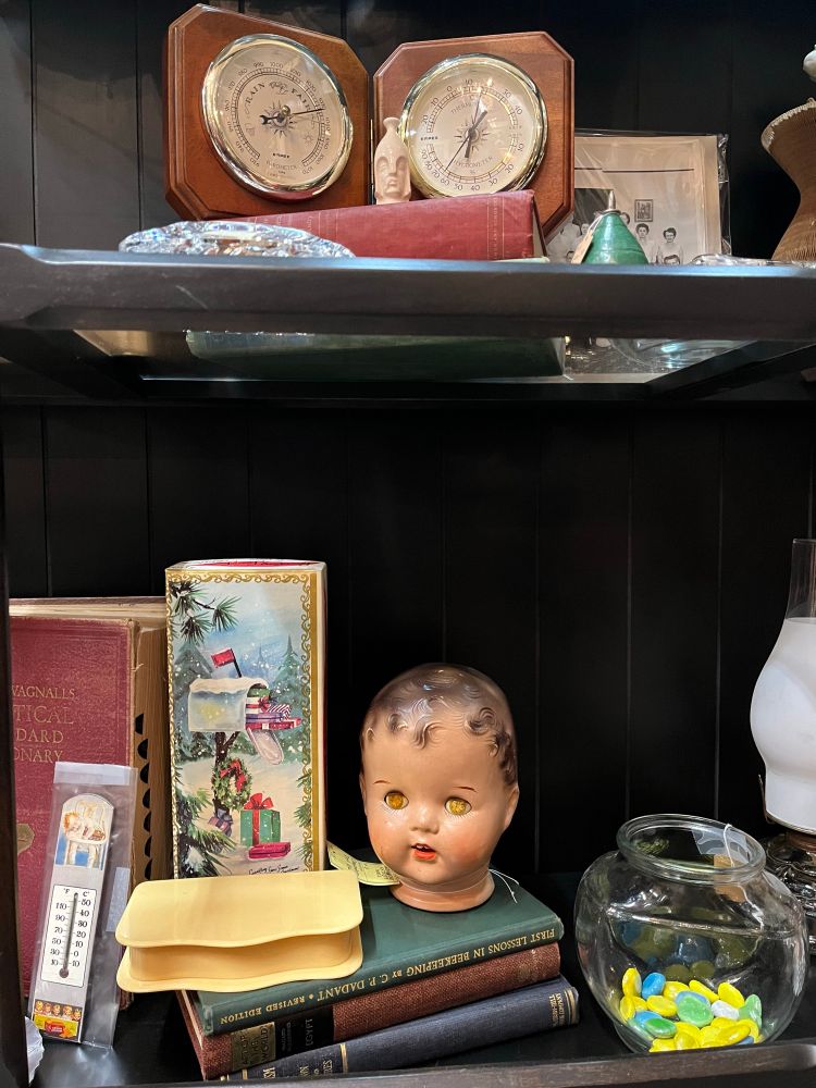 Miscellaneous antique store grouping with old hardbound books, some scientific instruments and a creepy old timer dolls head.  