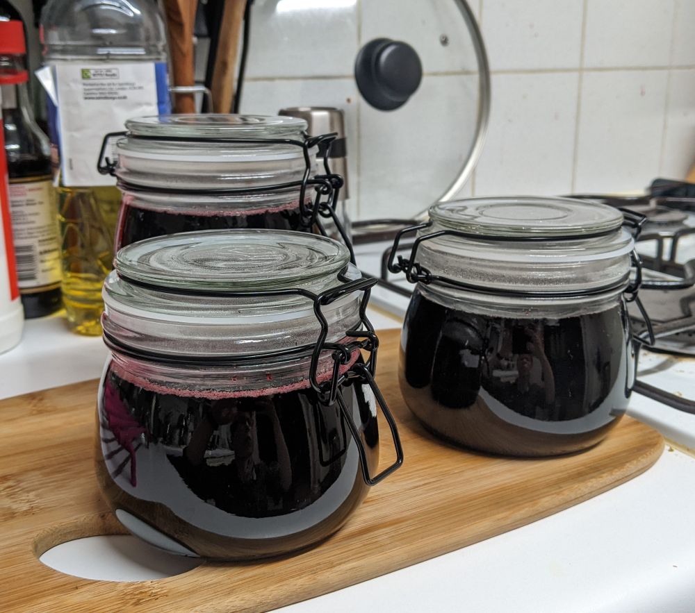 Three jars of liquid so dark it looks black, with a hint of red where it's foamed a little