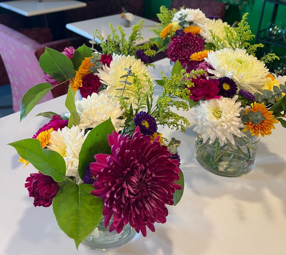 four mini floral arrangements for a business meeting at a local hotel where I spent my honeymoon staycation. each features chrysanthemums, asters, carnations, and some greenery. palette is magenta, white, purple, with pops of orange. 