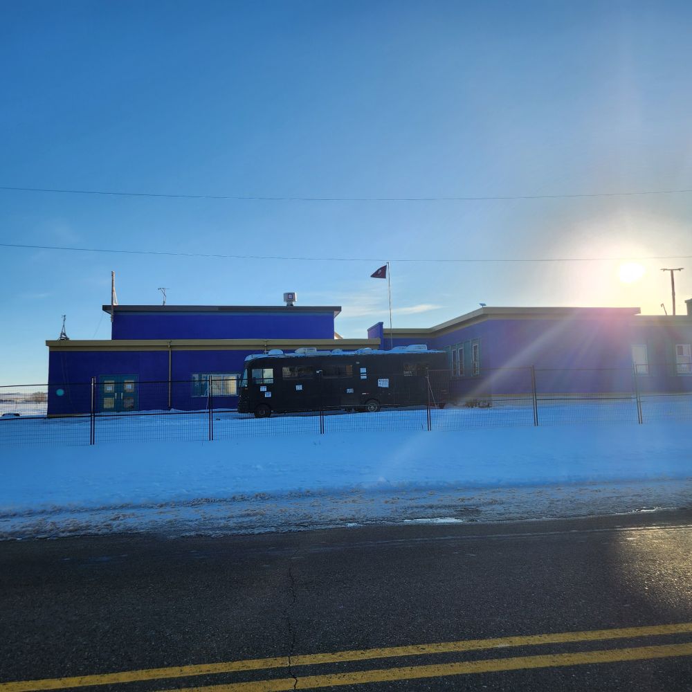 Sun is setting on the purple school in Richmound SK. Flag is tattered and needs replacing.