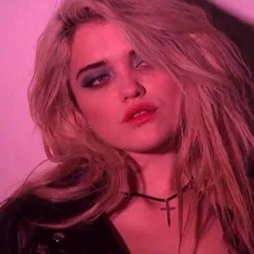 A mãe de todas nós, SKY Ferreira usa sombra azulada com delineado, tudo meio borrado, meio vestígio da noite passada. Ela tem o cabelo descolorido com raizes preta crescendo, usa jaqueta de couro e uma gargantilha com um crucifixo.