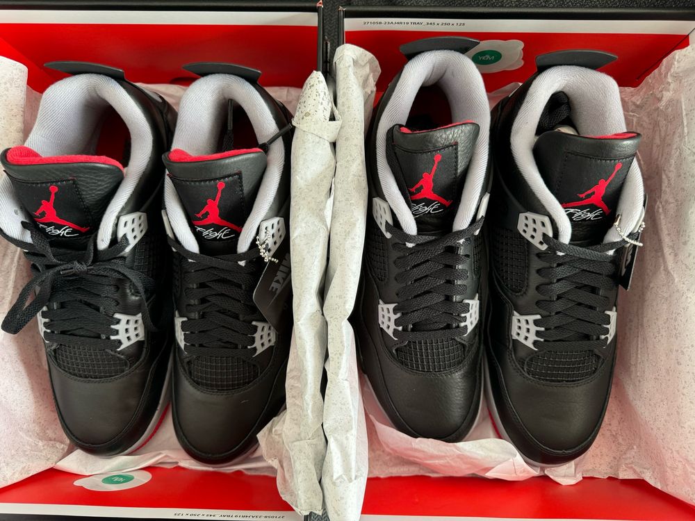 Top down view of two identical new pairs of Nike Air Jordan 4 in their boxes.