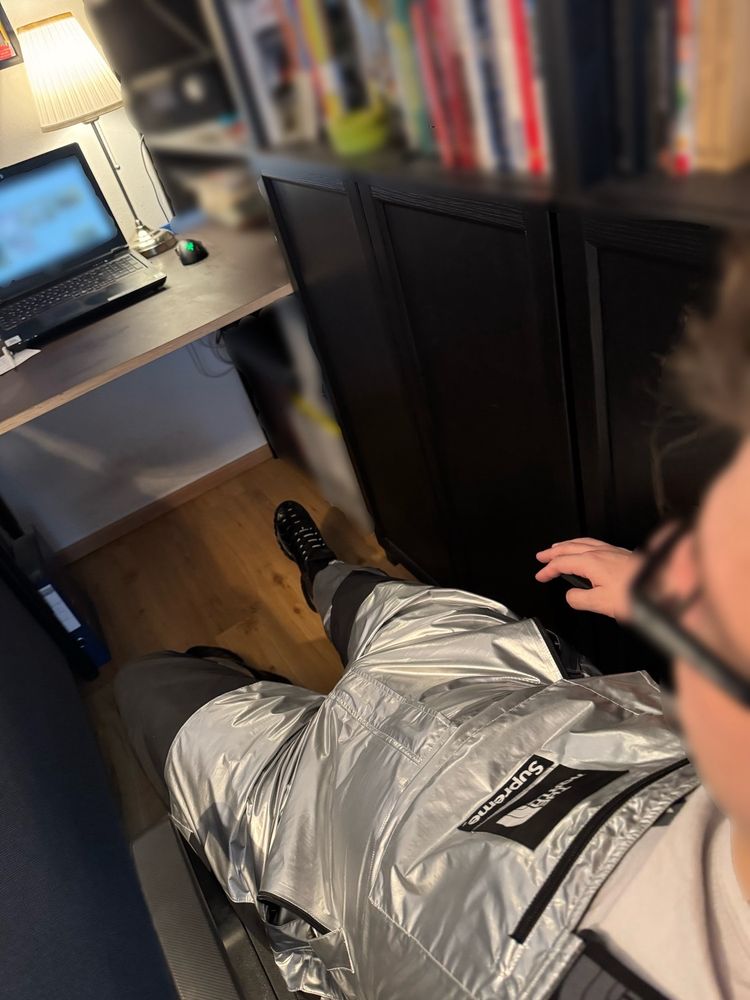 3rd person view over my left shoulder looking down towards my desk and floor. I’m wearing a shiny silver The North Face Supreme Bib and shiny black Nike TNs.