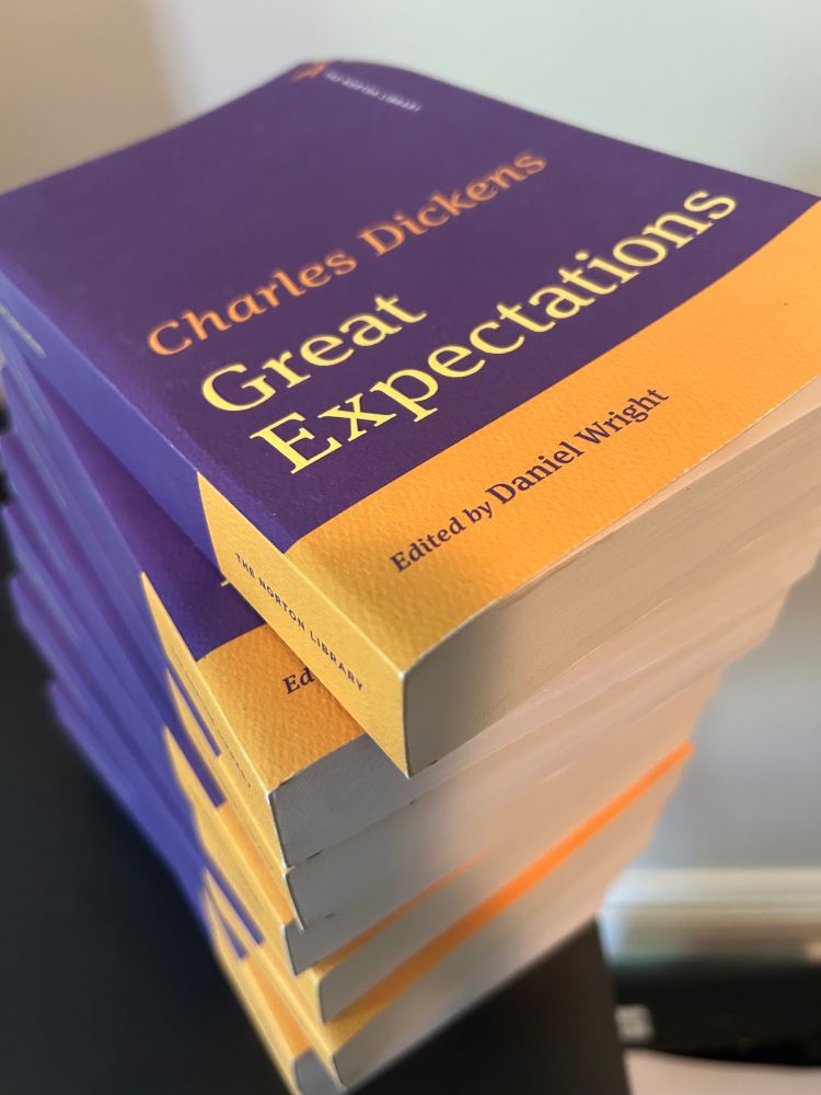 A stack of several purple-and-yellow copies of Charles Dickens's GREAT EXPECTATIONS, edited by Daniel Wright, Norton Library edition