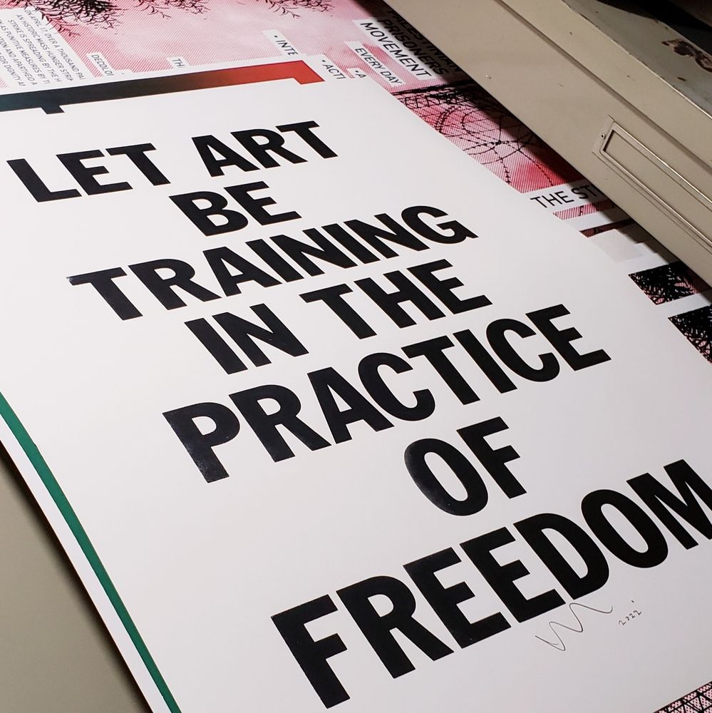 poster, by artist Kyle Goen, in open flat file drawer, white paper with all caps centered black lettering "LET ART BE TRAINING IN THE PRACTICE OF FREEDOM"