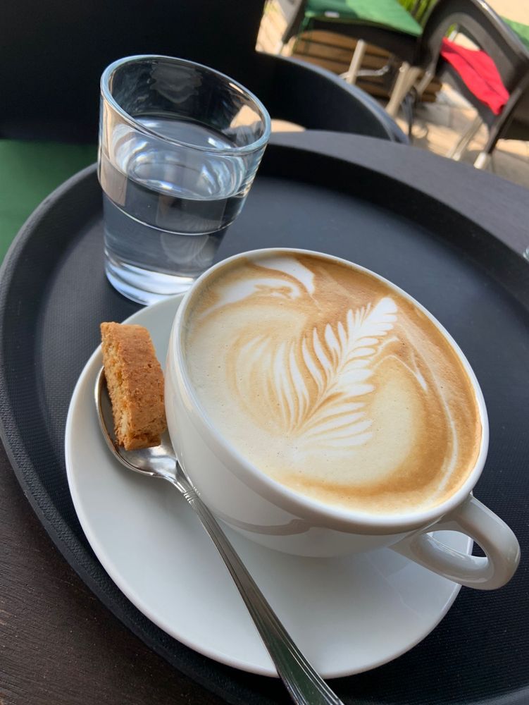 Tasse Cappuccino mit Keks und Wasser.