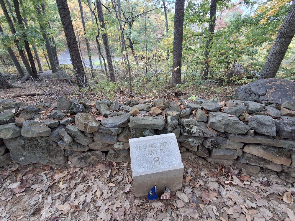 Marker for the line held by the 20th Maine regiment behind a low stone wall in the woods at Little Round Top