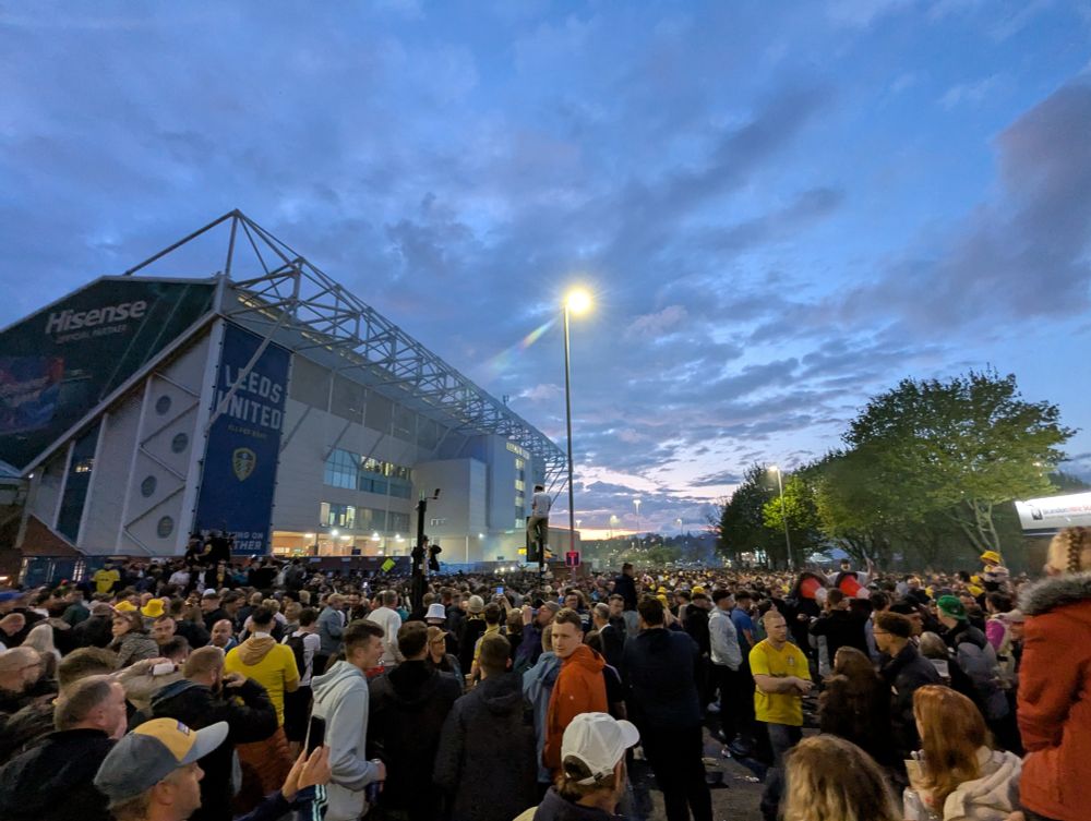 Photo of the crowd outside Elland Road after securing promotion to the premier league. The east stand is in the background as the sun sets over thousands of fans