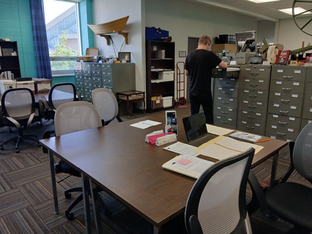 A reading room with large brown tables and filing cabinets along the wall.