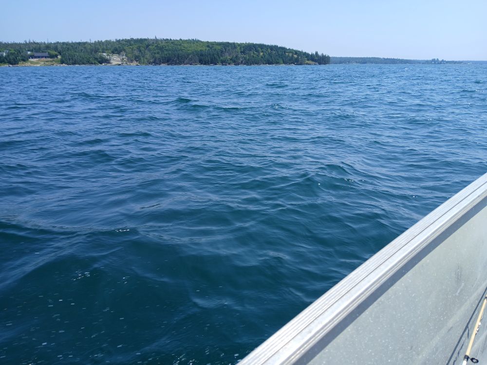 Blue water over the gunwhale of an aluminum boat.