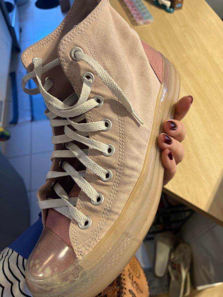 Foto de um Converse Rosa de cano alto segurado por uma mão de mulher com esmalte belíssimo licor 