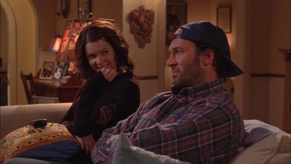 Lorelai eagerly watching Luke on her couch in Gilmore Girls