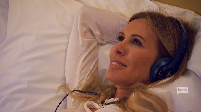 Childless icon Carole Radziwill lying in bed listening to music with a smile on her face
