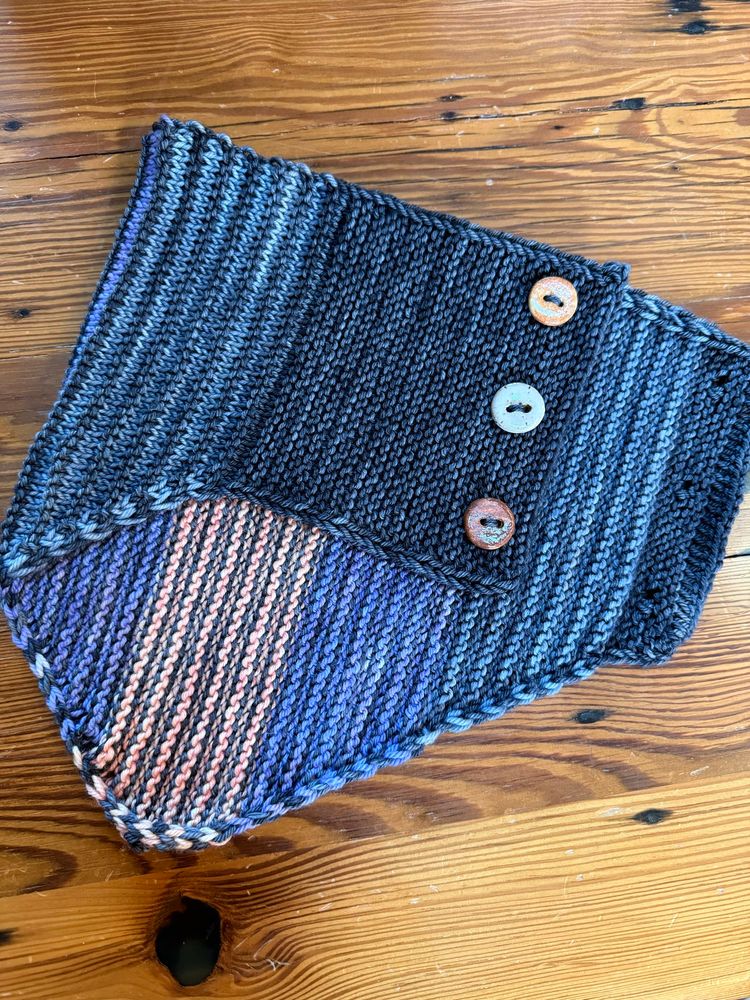 A flat lay of a striped multicolored cowl with buttons 