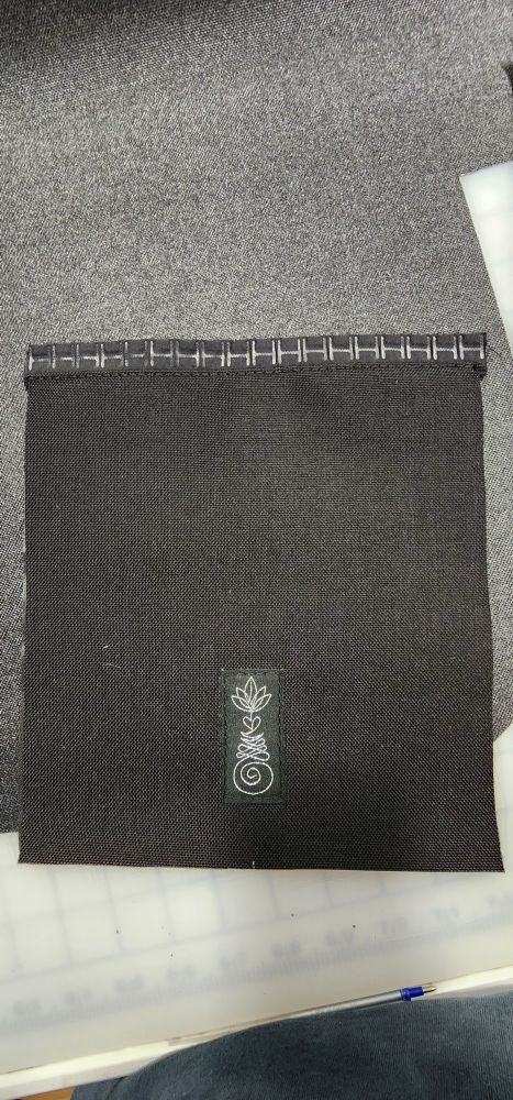 Black Cordura fabric with the unalome logo in the center and magnetic zipper sewn on at the top.