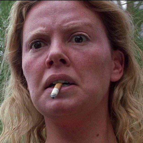 Aileen Wuornos portrayed by Charlize Theron, with a cigarette butt hanging out of her mouth 