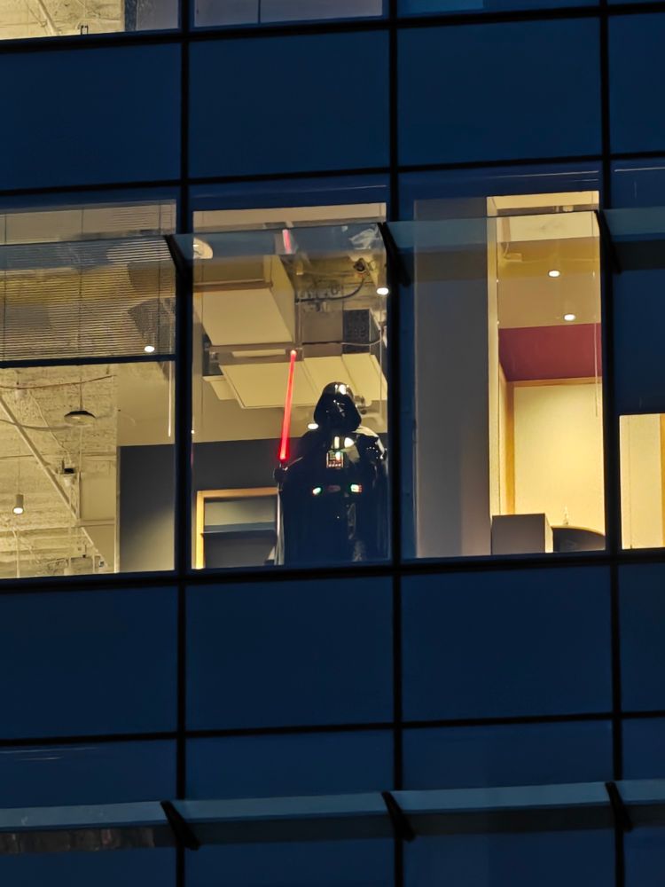 Darth Vader looking down through a window in a Microsoft Office Building. 