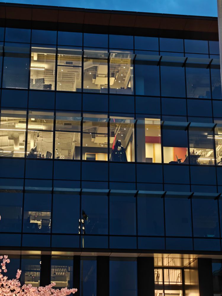 Darth Vader looking down through a window in a Microsoft Office Building. 