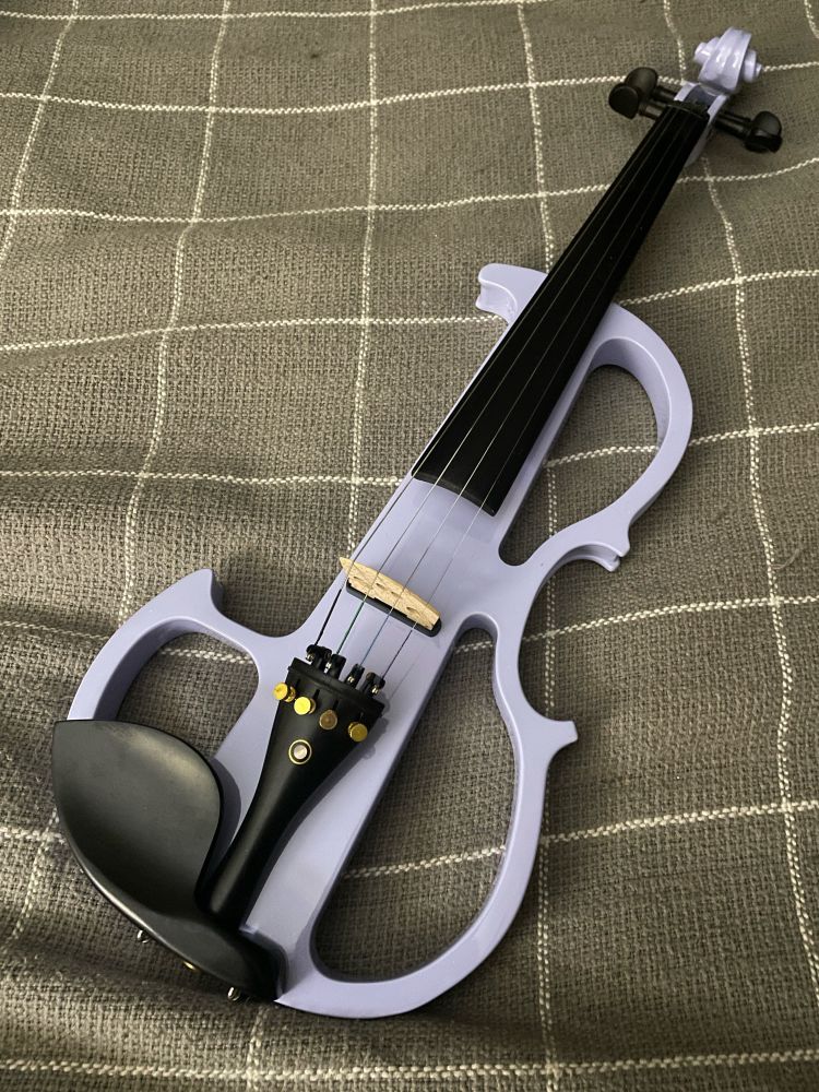 A lavender electric violin sits on a dark gray blanket with thin white lines. 