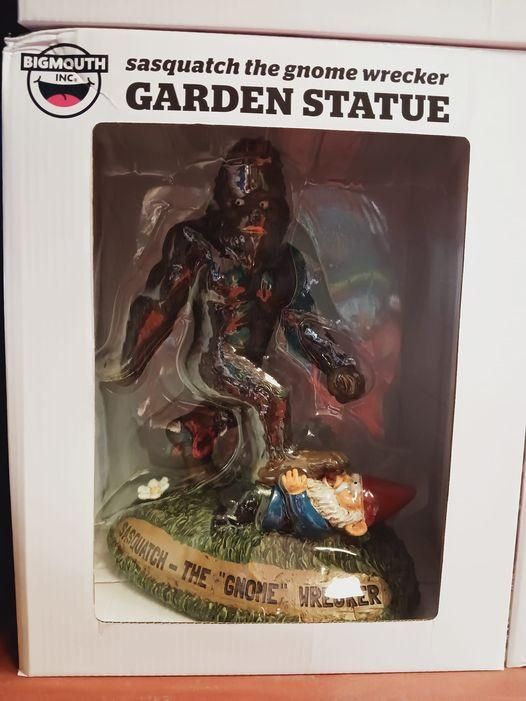 A garden statue display in package of a bigfoot stomping a garden gnome statue. Label reads "sasquatch the gnome wrecker"