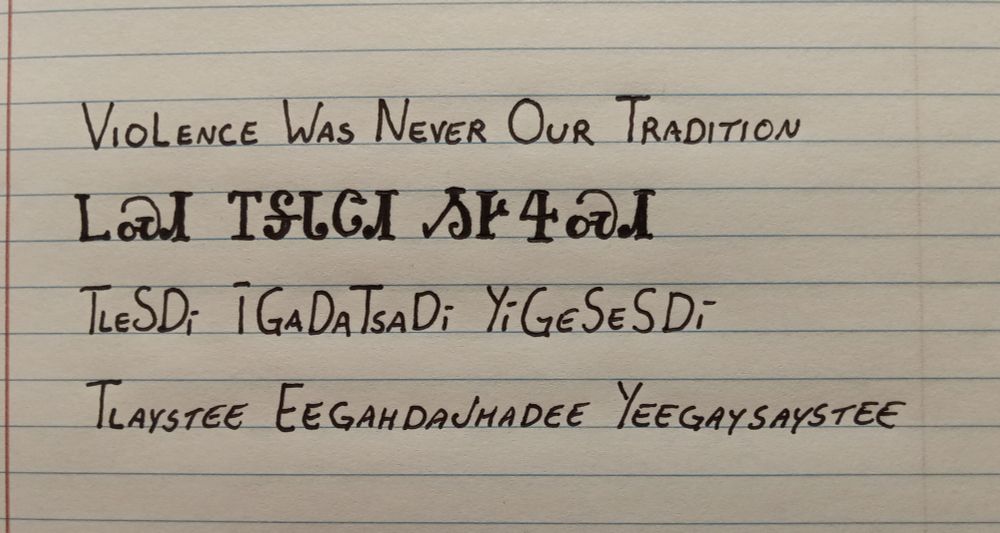 Image is line paper with writing showing an English word followed by how it is written in the Cherokee language followed by how it is spelled and pronounced. The words are violence was never our tradition and pronounced tlaystee eegahjhadee yeegaystaystee