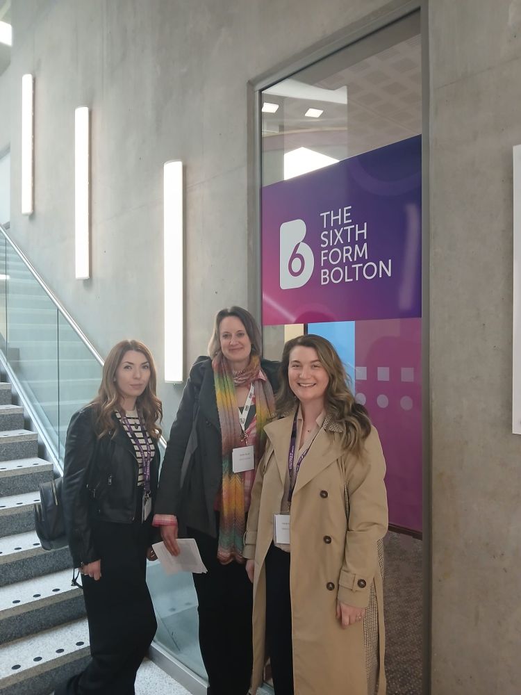 Staff and students of occupational therapy in front of a Bolton sixth form sign
