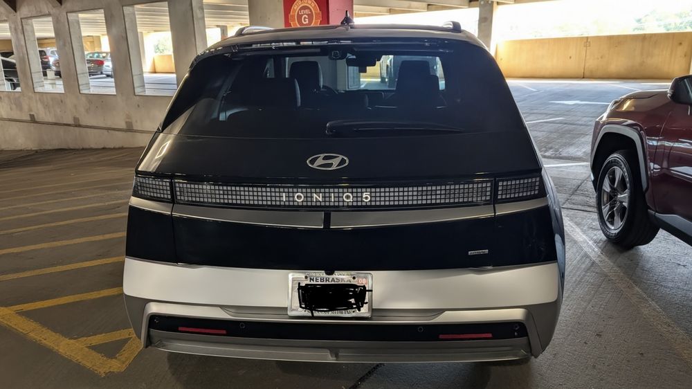 The rear of a 2025 Abyss Black Hyundai Ioniq5 Limited AWD that is parked in a garage. License plate obscured for privacy reasons.