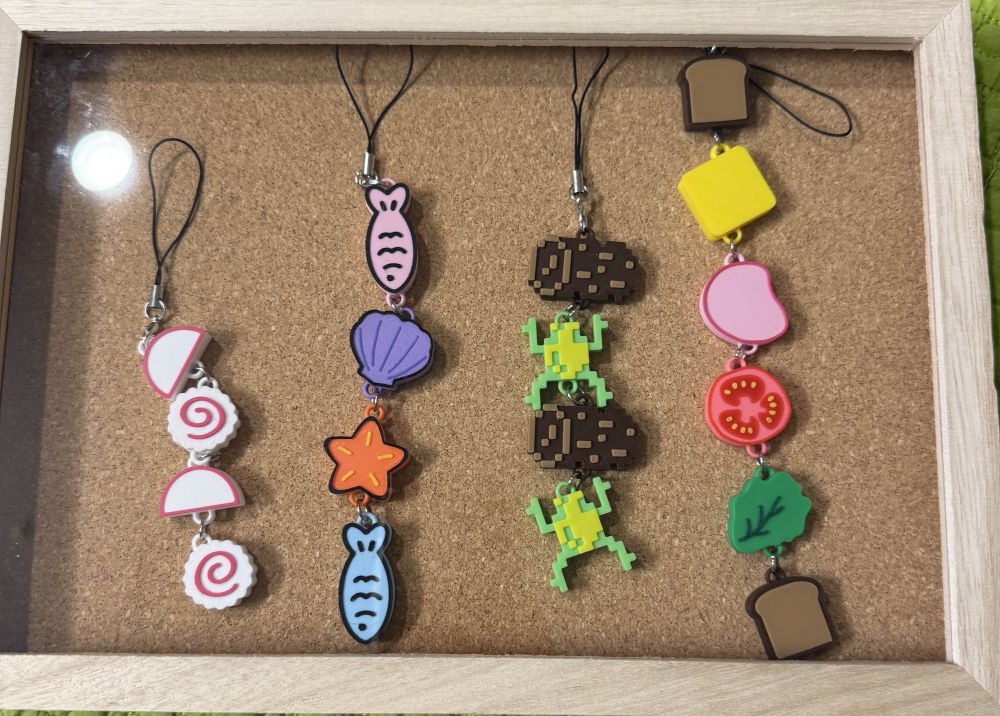 3d printed keychains designed by saunafrog displayed on a cork board.
LEFT to RIGHT: fishcake keychain, ocean themed keychain, frogger keychain, deconstructed sandwich keychain