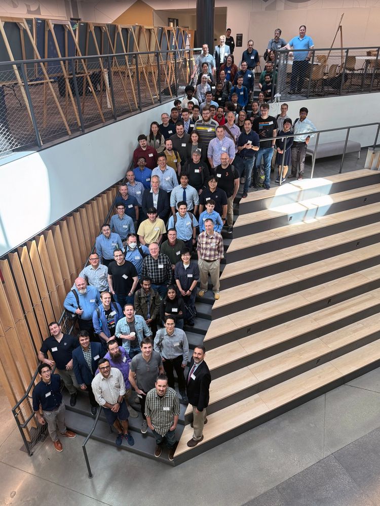 a group of conference attendees standing on an inside stairway looking up at the camera