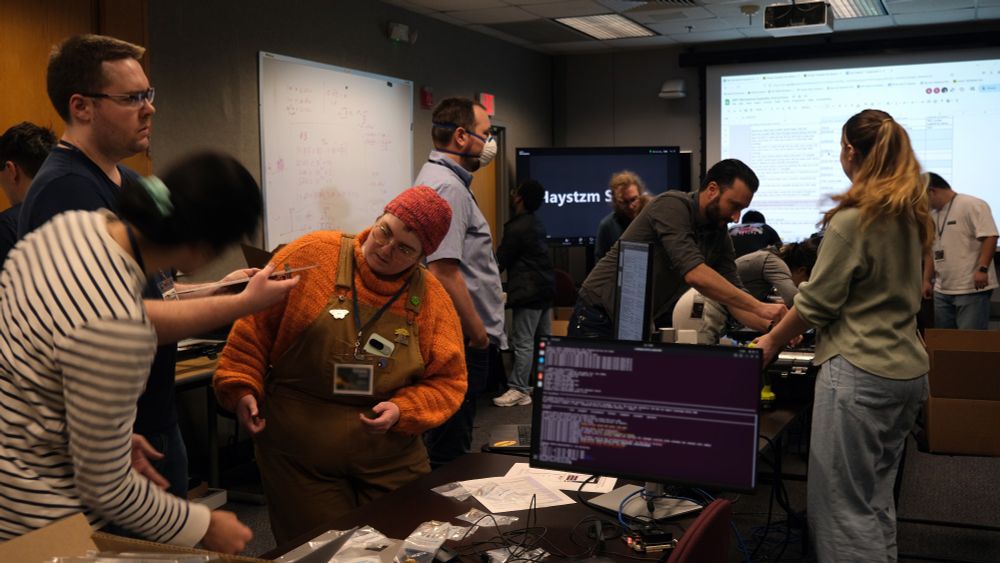 a group of undergraduate students working on a technical device near a computer monitor