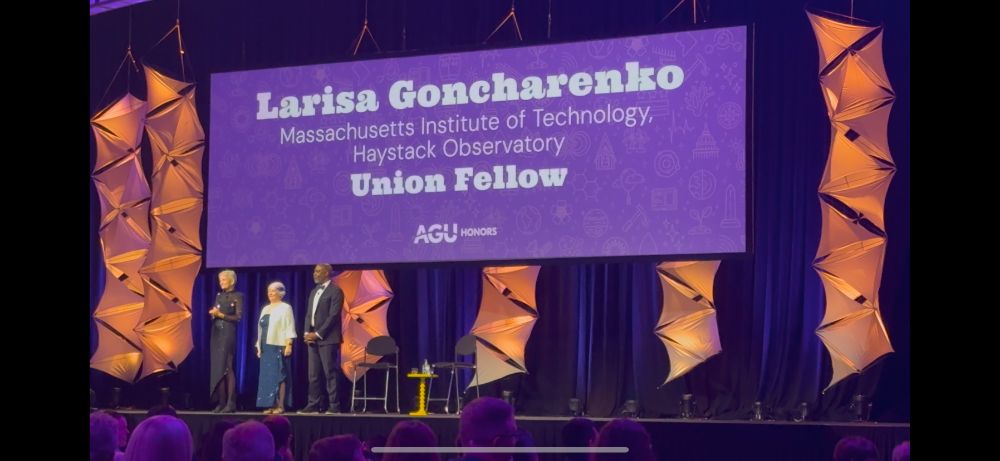 Larisa Goncharenko accepting her award as AGU 2024 Union Fellow under a large purple sign