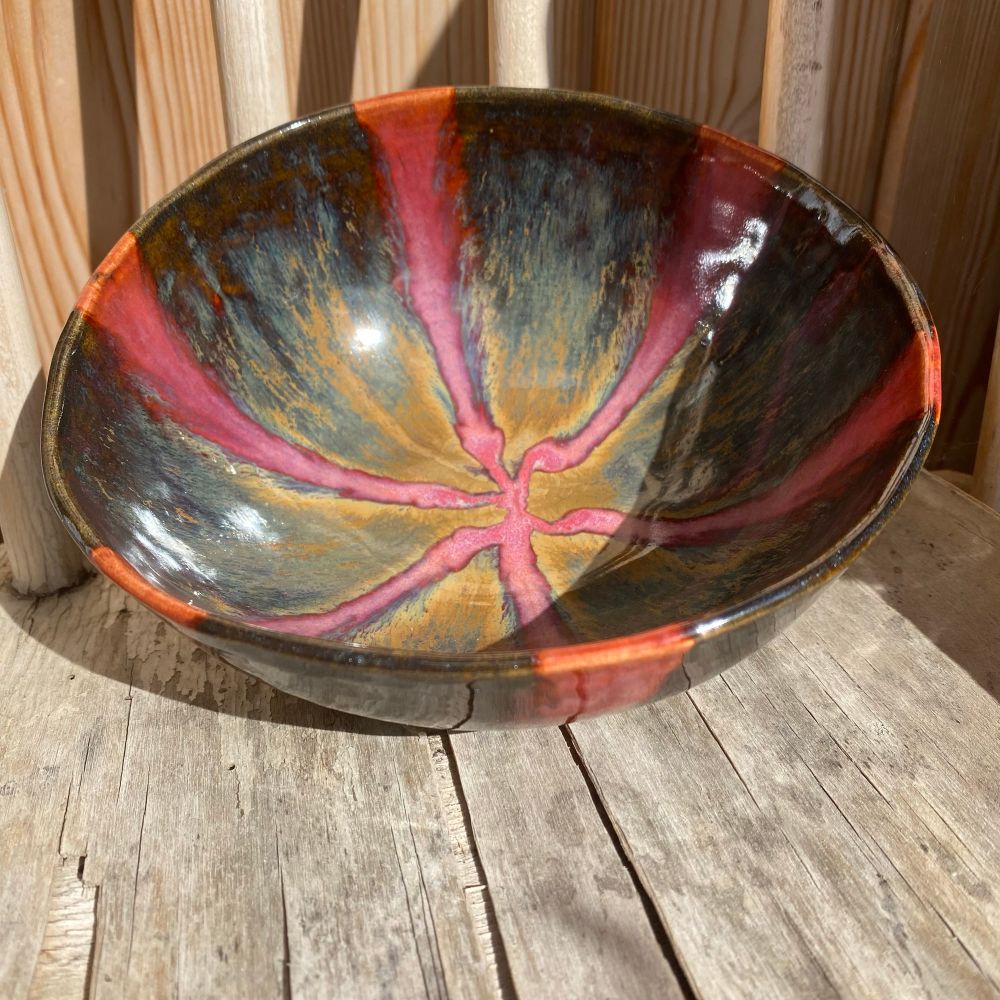 Ceramic bowl glazed in dark brown triangles with pink stripes between them, all meeting at the centre bottom of the bowl