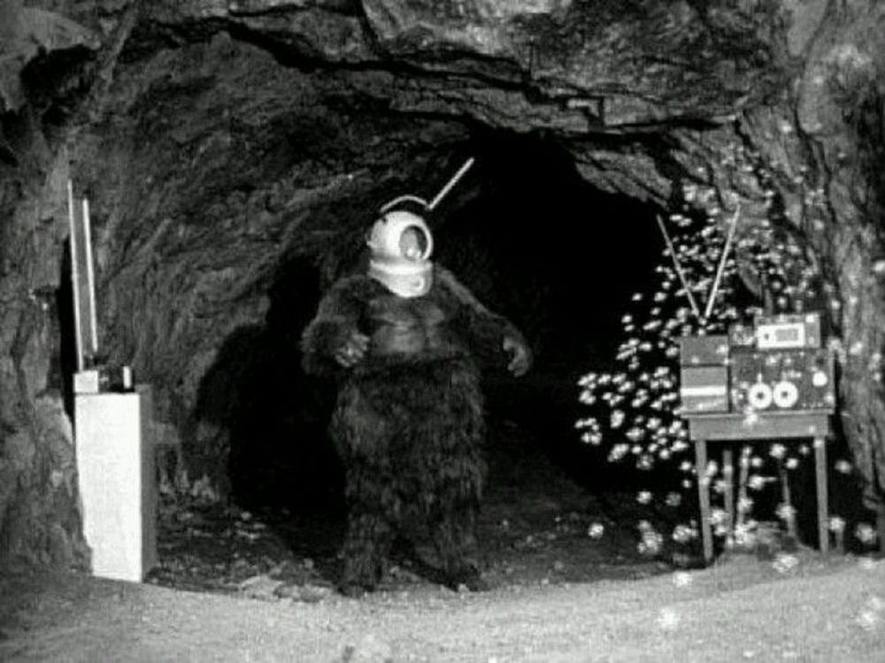 Ro-Man, a robot with the body of a gorilla and the helmet of an astronaut, with two antenna coming out of the helmet, stands handsomely in the entrance to a cave. All must fear Ro-Man!