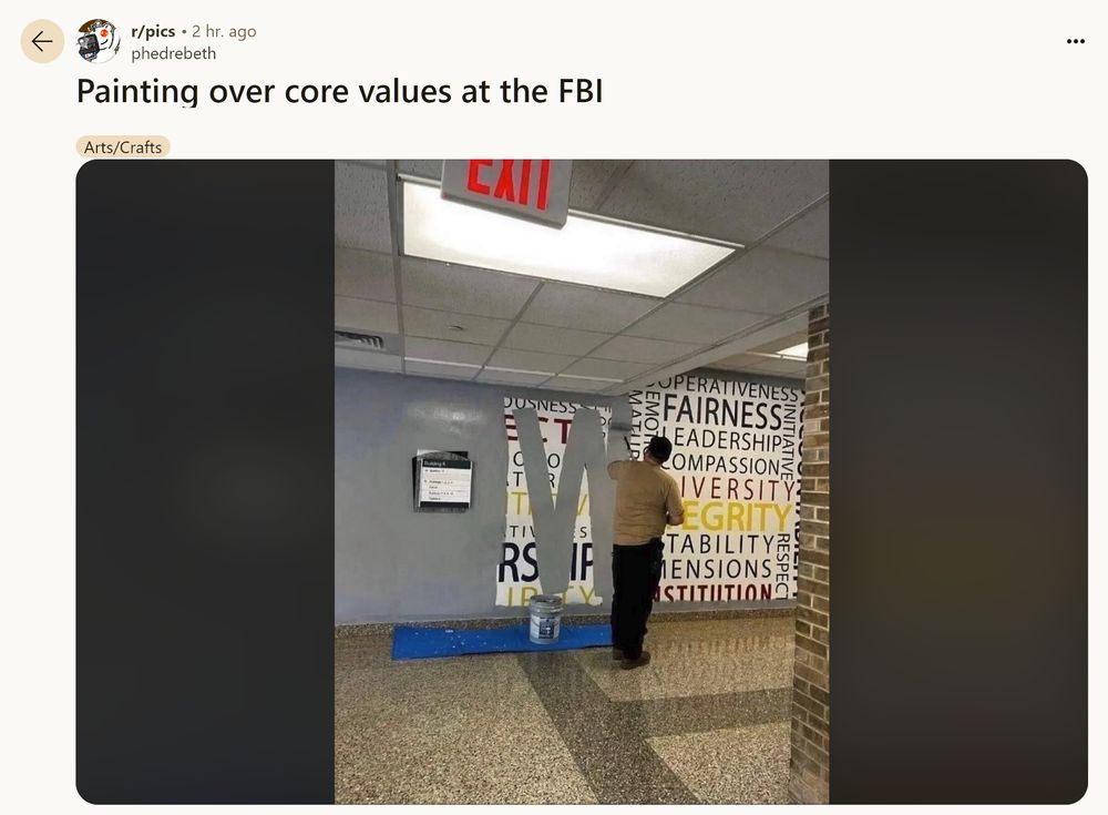 A main paints over a wall full of "values" like fluff on a wall at the FBI. The new paint is a bland grey to symbolize the pettiness and lack of emotion from the current administration. The image was posted to the subreddit r/pics with the title "Painting over core values at the FBI" and has the tag "Arts/Crafts"