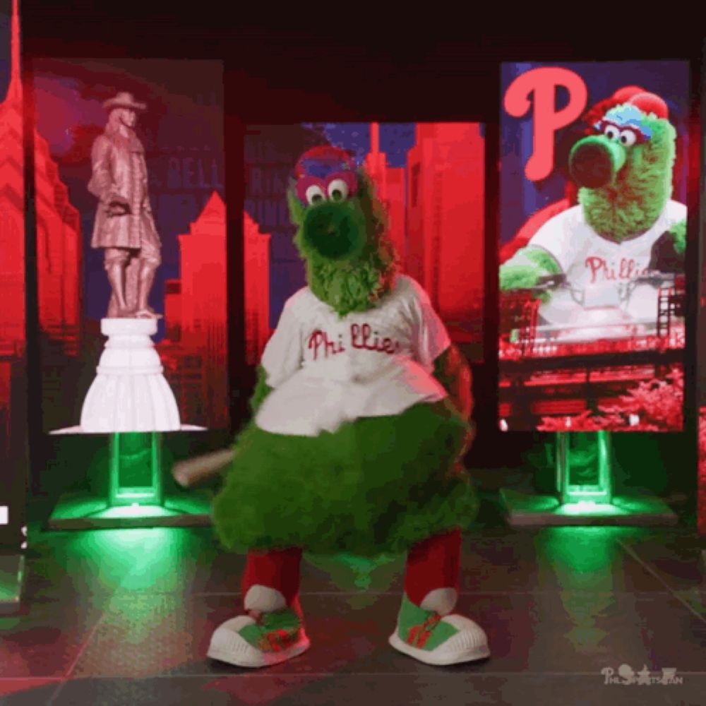 a mascot for the phillies is dancing in front of a large screen