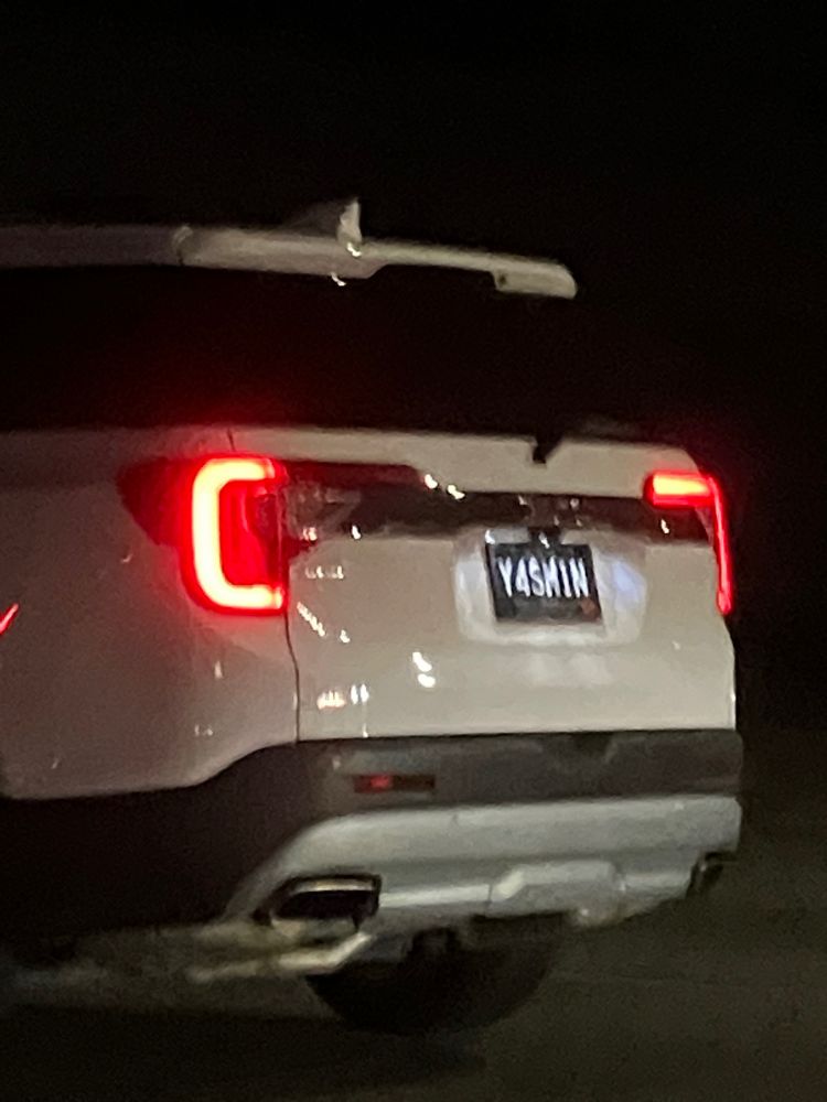 A photo of a white SUV with a custom license plate that uses letters and numbers to create the name YASMIN 