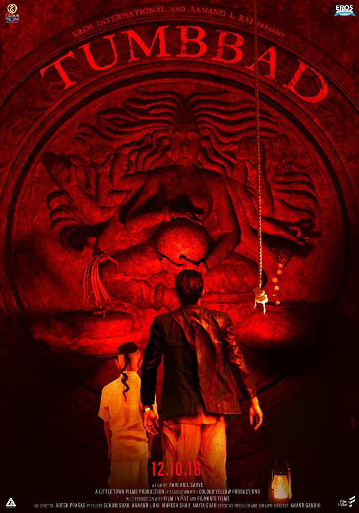 Poster for Tumbbad. A red colored image showing a father and his son looking at a sculpture of a pregnant goddess.