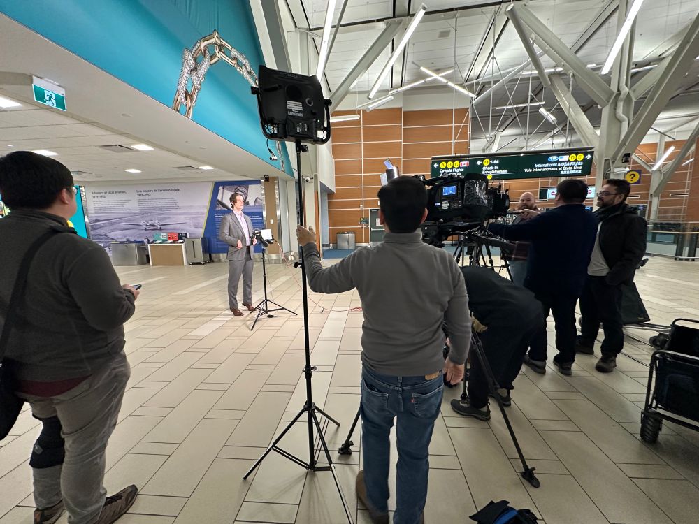 A stand-in checking mikes and lights in front of cameras outside the ABC departure gates at YVR