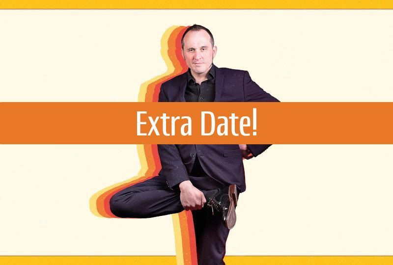 Photo of Phil Ellis in a dark suit, holding one leg tucked up in a comically awkward pose a bit like a flamingo. An orange banner with the text 'Extra Date!' in white, overlaid across the middle of the image.