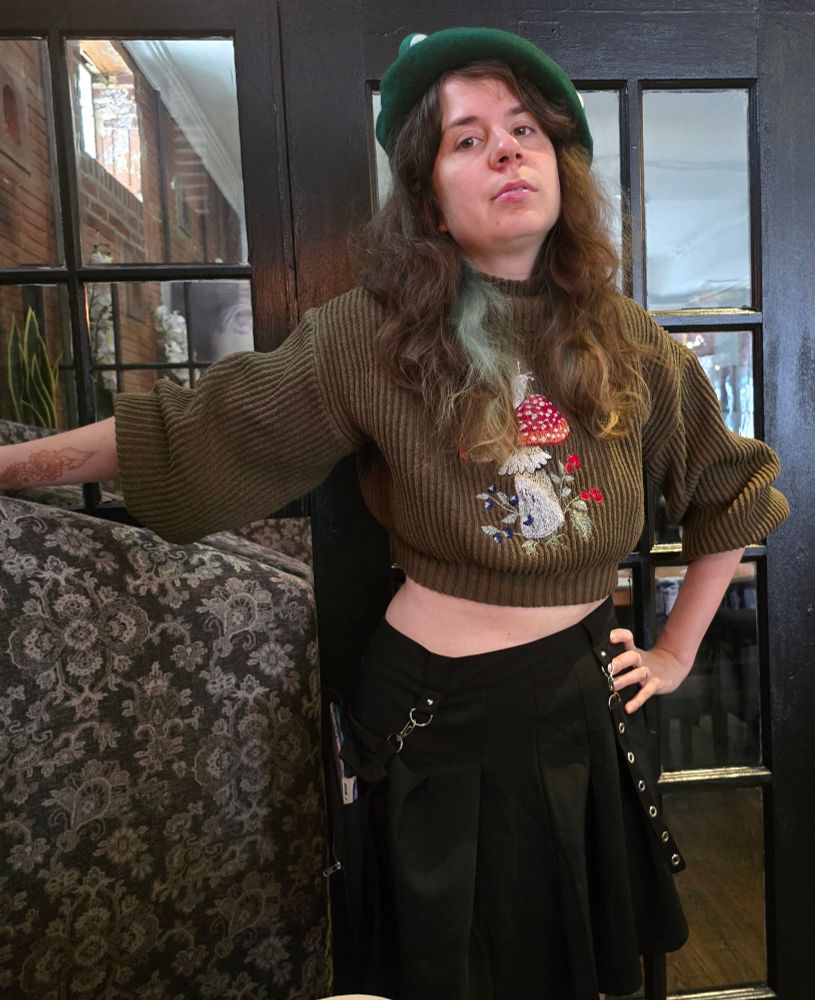 Jax in a fancy brunch place in a mini skirt and green frog beret and cropped sweater 