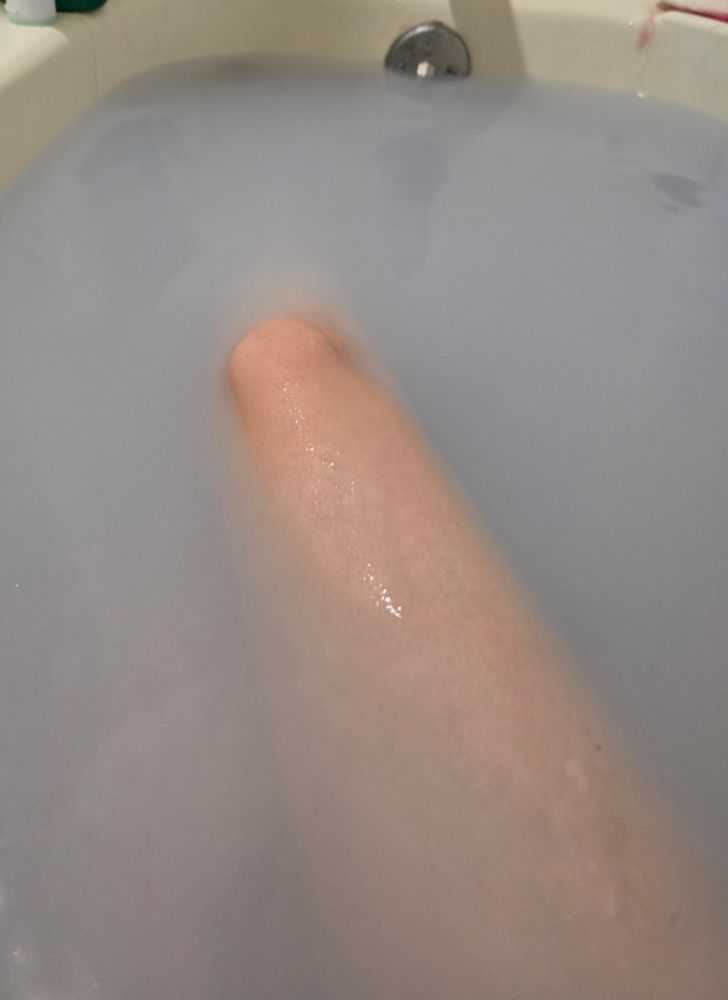 a knee peeks out of silver-purple water