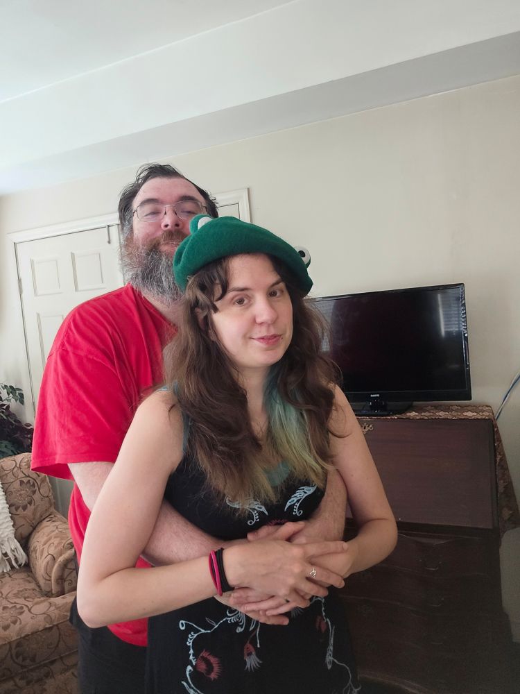 Jax stands with her husbando's arms wrapped around her